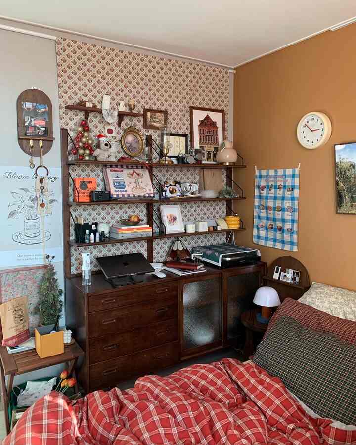 ベージュとブラウンの色調の小さな寝室、ヴィンテージ家具と壁棚に様々なヴィンテージ小物が配置された雰囲気のあるインテリア