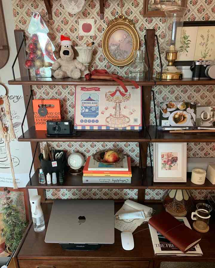 ヴィンテージ壁紙が貼られたワンルームのホームオフィス、木製のデスクと本棚にノートパソコンや装飾品が配置された落ち着いた作業空間