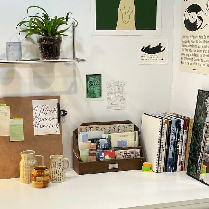 White and brown toned home office desk space featuring assorted posters and organizers in a tidy workspace interior