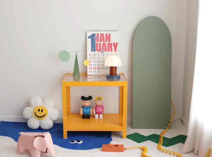 青と黄色を基調とした子供部屋、玩具収納、モビール、テーブルランプが置かれた明るくシンプルなインテリア