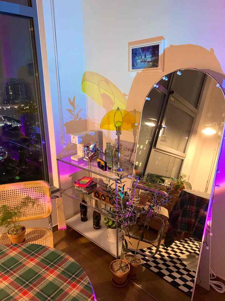 Light natural toned living room featuring round dining table, rattan chairs, and a large arched full-length mirror with cozy ambiance