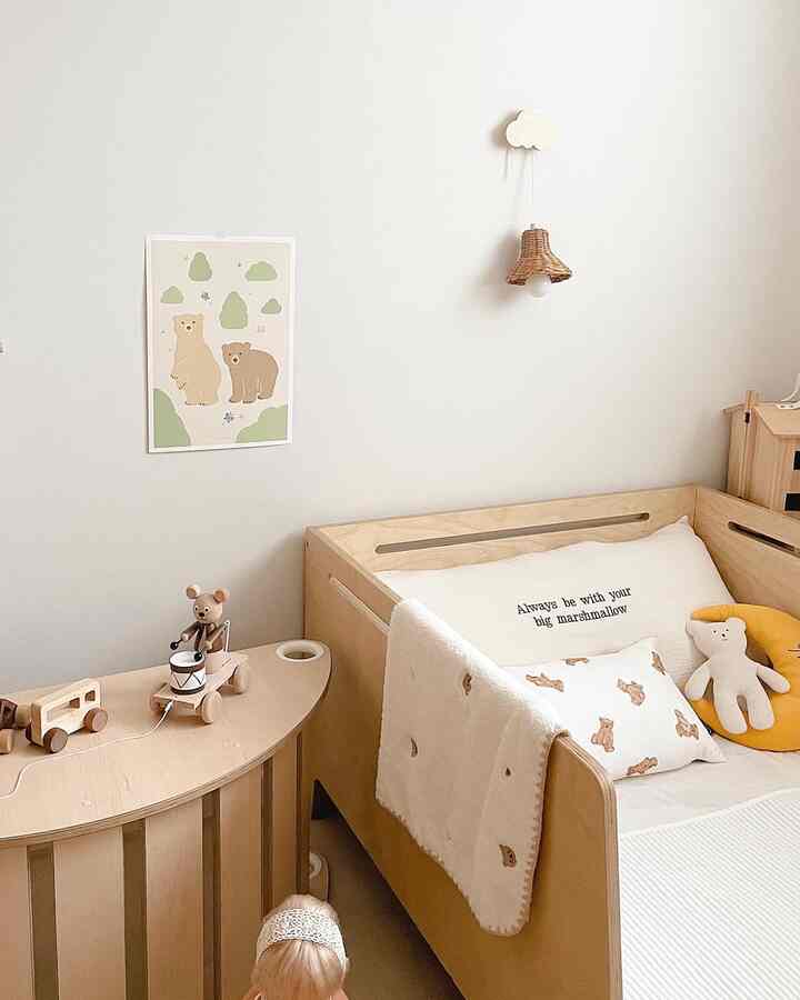 ナチュラルな色調の子供部屋、木製のベビーベッドと子供向けポスターが配置された温かみのある空間
