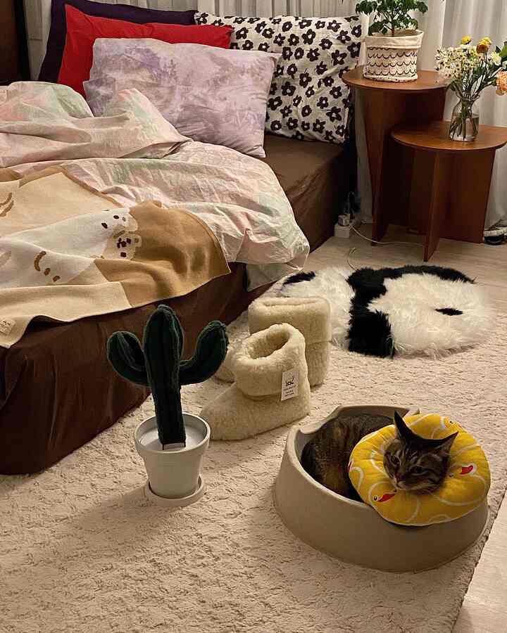 ベージュとナチュラルカラーの寝室、ふわふわスリッパと猫用ベッドが置かれた雰囲気のある空間