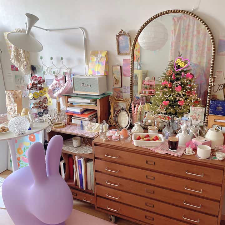 Pastel toned living room featuring vintage furniture, various objet d'art, and a large mirror creating a cozy atmosphere