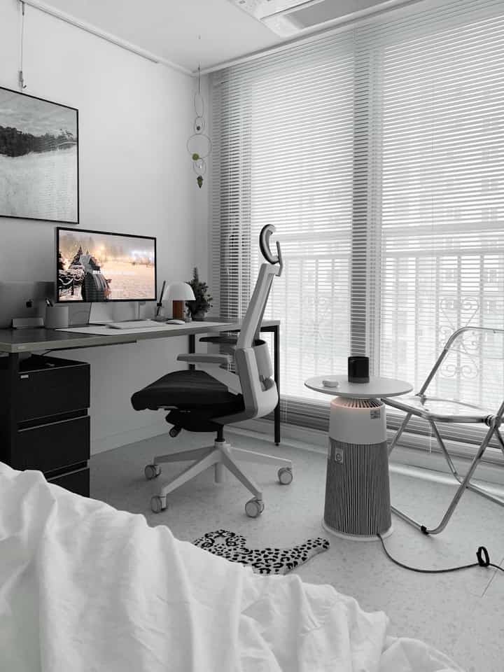 White and black toned studio apartment home office featuring computer desk and office chair in a clean modern setting
