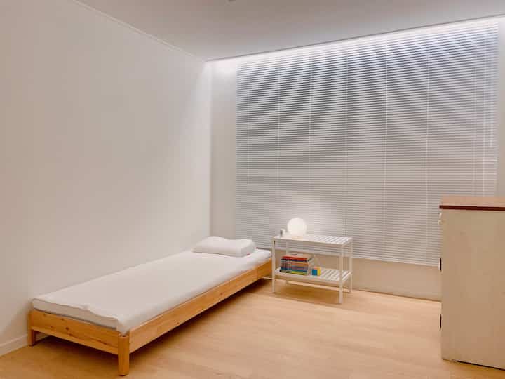 白と木目調の子供部屋、低いベッドとナイトテーブルが配置されたシンプルで落ち着いた睡眠スペース