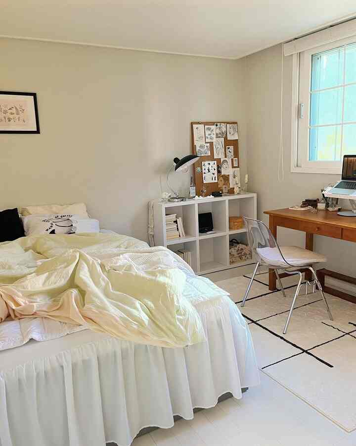 Bright white and wood tone bedroom featuring a cozy bed, desk, and bookshelf in a warm, inviting atmosphere