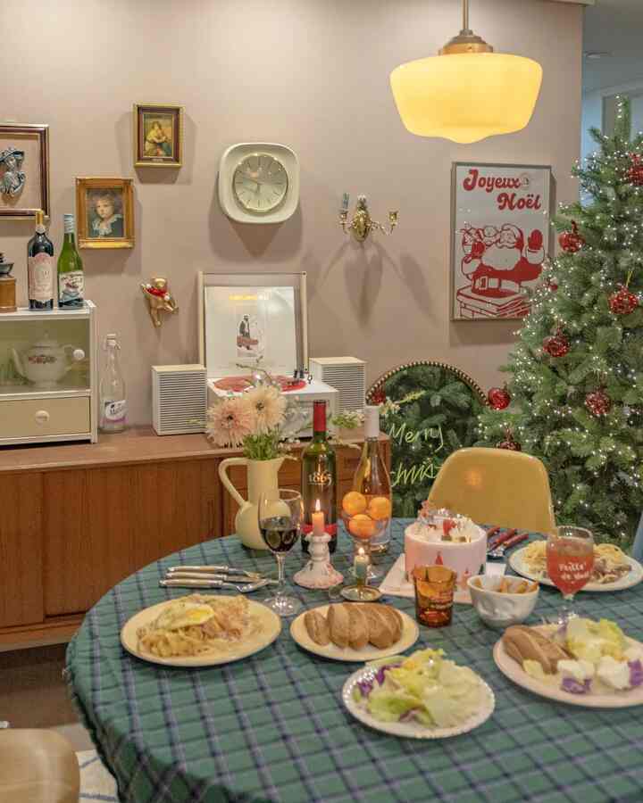 白い壁とヴィンテージ家具が調和するダイニング、クリスマスツリーとホームパーティーの食卓が配置された雰囲気のあるインテリア