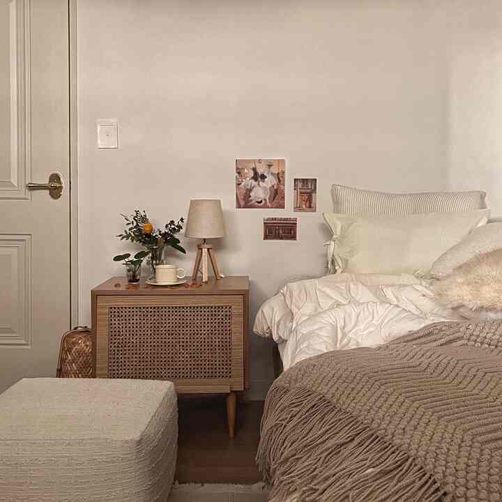 Beige and wood tone bedroom featuring bed, nightstand, and table lamp creating a cozy warm atmosphere.