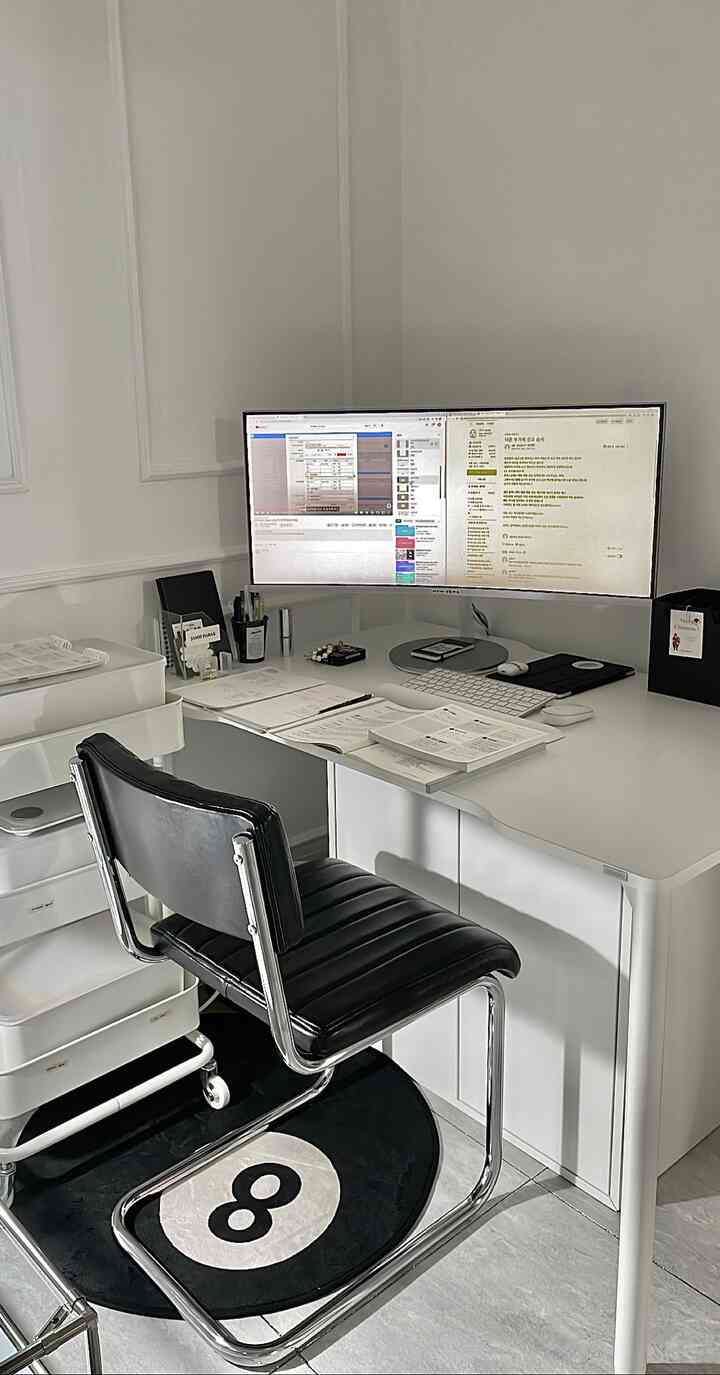White and black toned home office space featuring a large dual-monitor desk and black leather office chair in a tidy setup