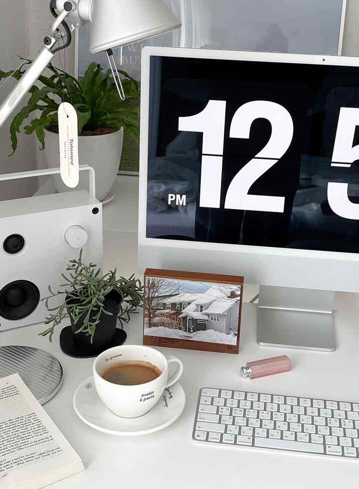 White-toned home office space featuring an iMac, wooden objet calendar, and a coffee cup on a tidy desk