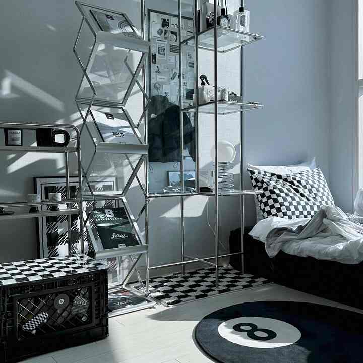 Monotone toned bedroom space featuring checkerboard patterned cushions and rug, modular furniture creating a modern and clean interior