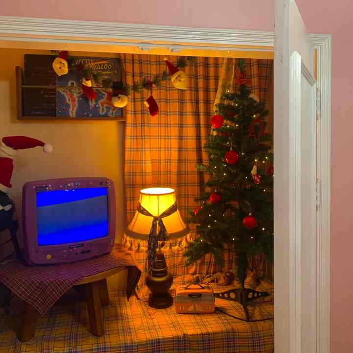 オレンジ色のチェック柄カーテンとヴィンテージスタイルの小物が配置されたクローゼット内のクリスマス装飾スペース