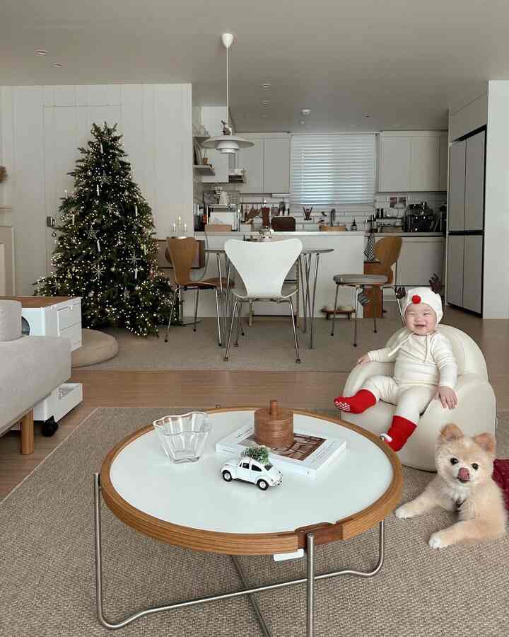 ホワイトとブラウンの色調のリビング、クリスマスツリーとベビーソファ、犬がいる暖かく居心地の良い空間