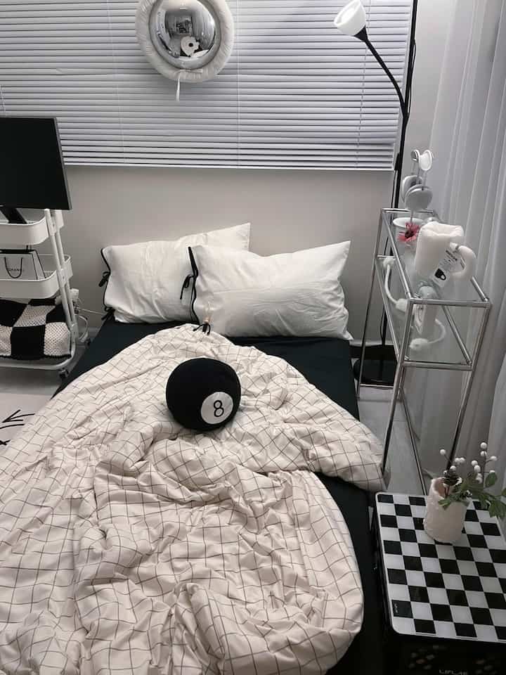 A white and black toned single household bedroom featuring a simple modern bed and blinds