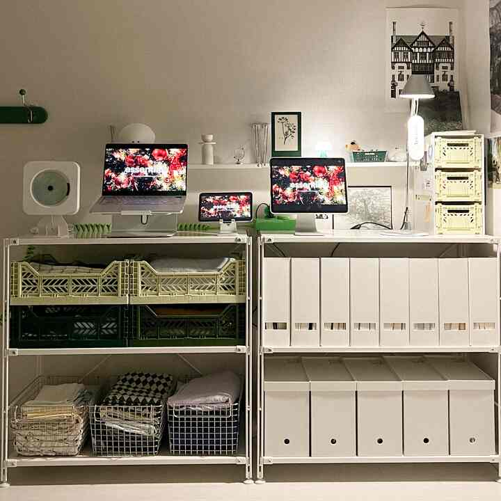 White and light gray toned home office space featuring multiple electronic devices and unit shelves with neat storage in a modern design