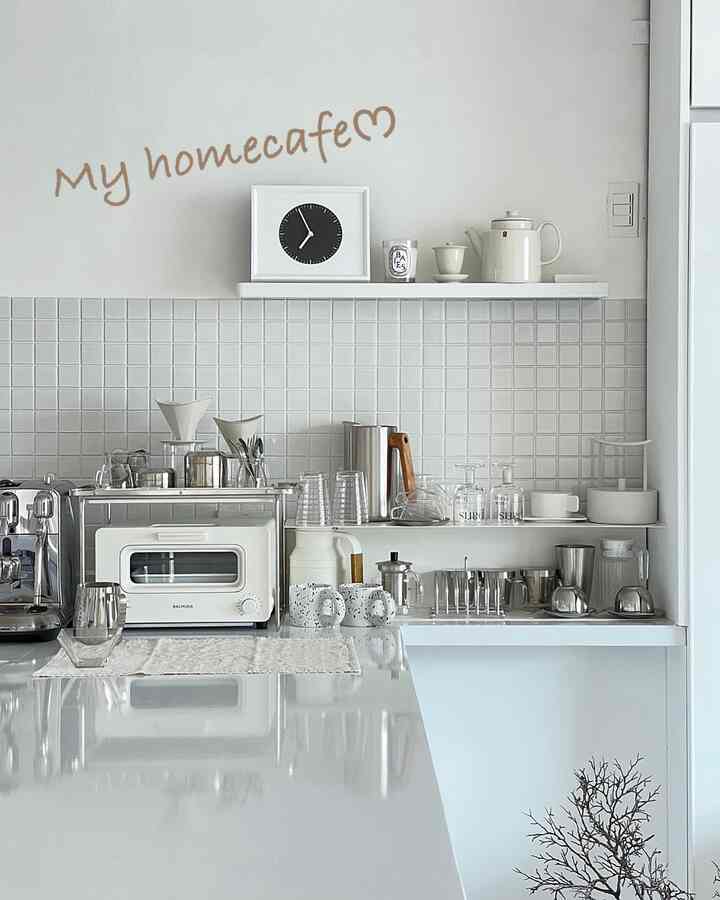 白を基調としたミニマルなキッチン、コーヒーマシンやトースターなどがおしゃれに配置された印象的なインテリア