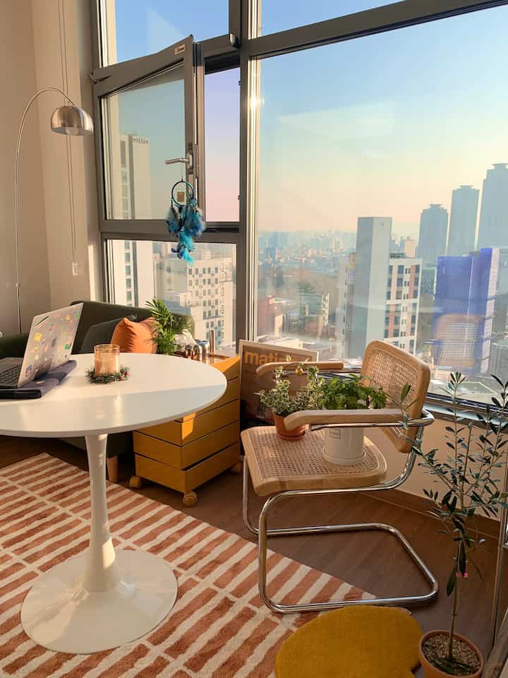 ブラウンとホワイトのトーンのワンルームリビング、モダンなミッドセンチュリースタイルのソファとラグが調和する雰囲気のある空間