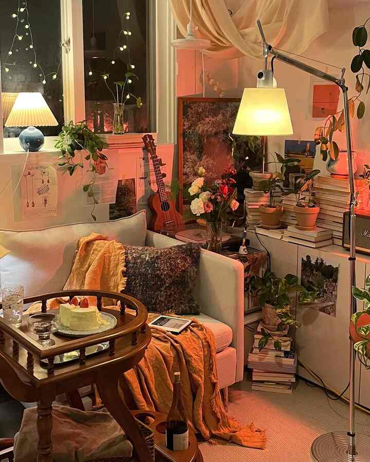 Warmly lit vintage living room with a cozy sofa, multiple plants, flowers, and a wooden coffee table in a single household setting