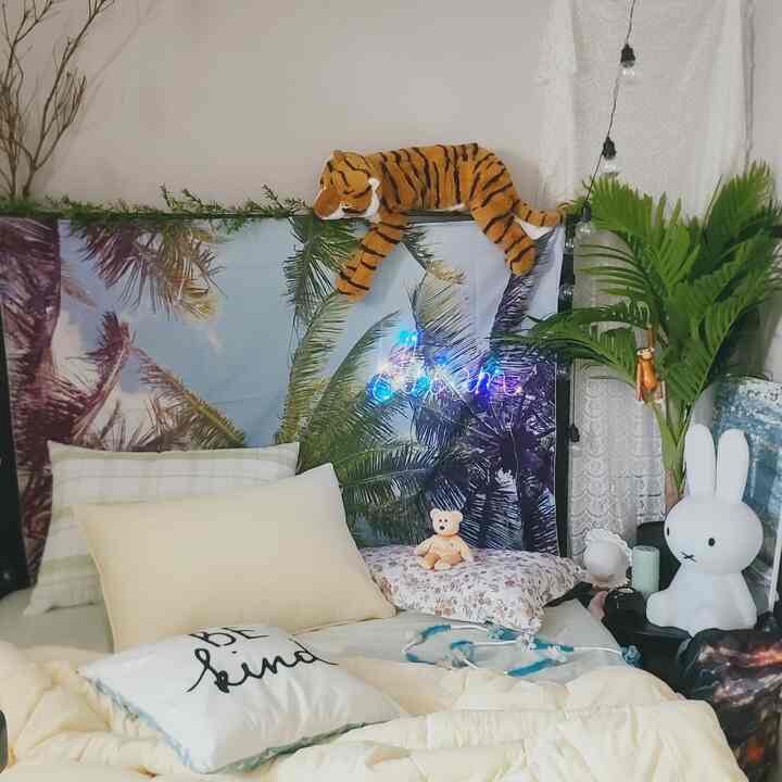 Cozy bedroom in white and beige tones featuring multiple cushions and plants, evoking a warm and natural ambiance