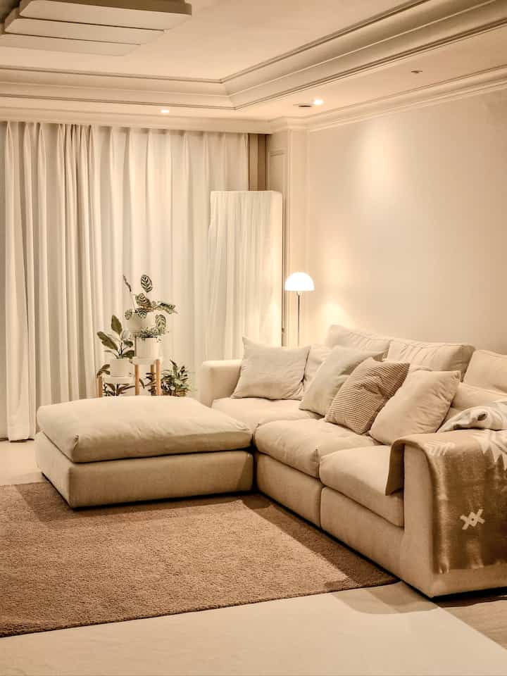 Beige and natural tone living room featuring a modular sofa and floor lamp in a cozy atmosphere