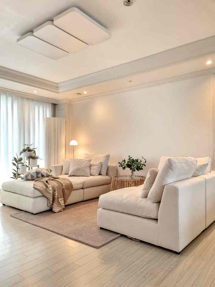 Natural beige-toned living room featuring cream modular sofas, beige rug, and bright white curtains creating a cozy atmosphere