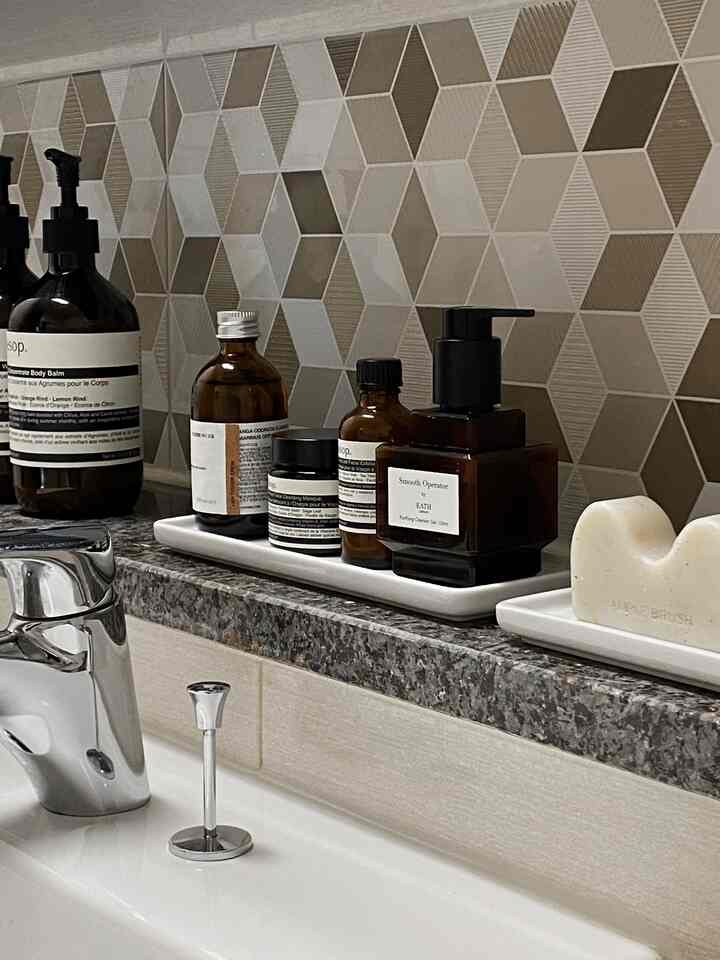 Beige and white toned bathroom with neatly arranged toiletries on white trays, creating a clean atmosphere