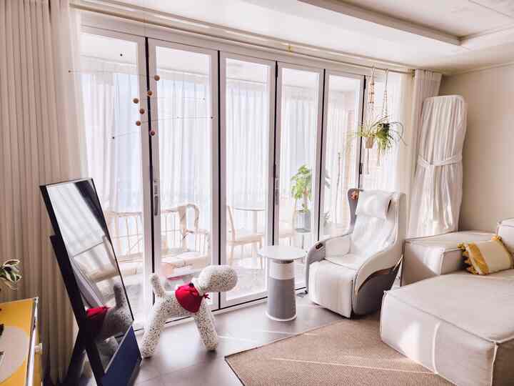 Bright and cozy living room in white and beige tones, featuring large glass doors and dog-shaped decor for a pet-friendly vibe