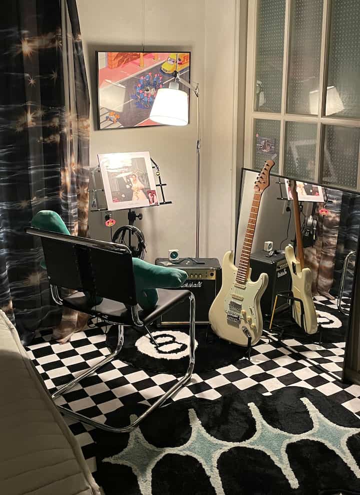 Black and white themed music room featuring an electric guitar, checkered rug, and floor lamp with a modern vibe
