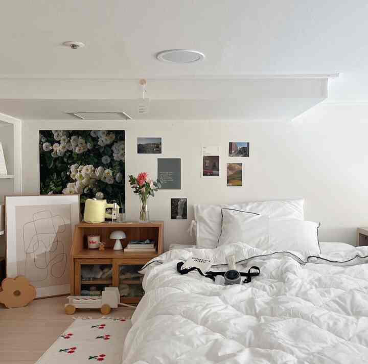 White and wood tone bedroom featuring white bedding, wooden cabinet, and floral wall art in a natural ambiance