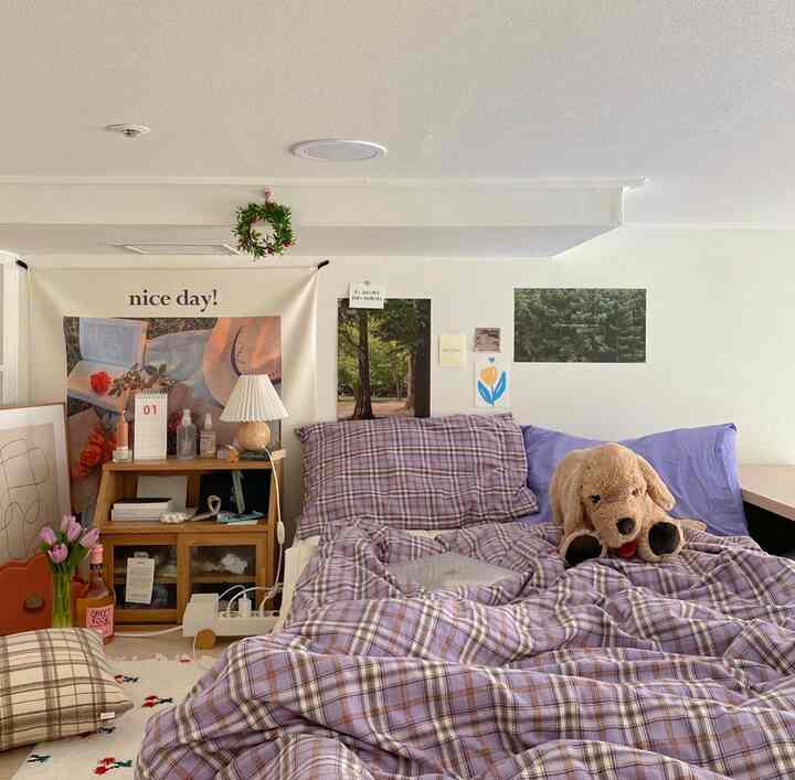 Natural bedroom featuring purple plaid bedding and a dog plush toy creating a cozy atmosphere