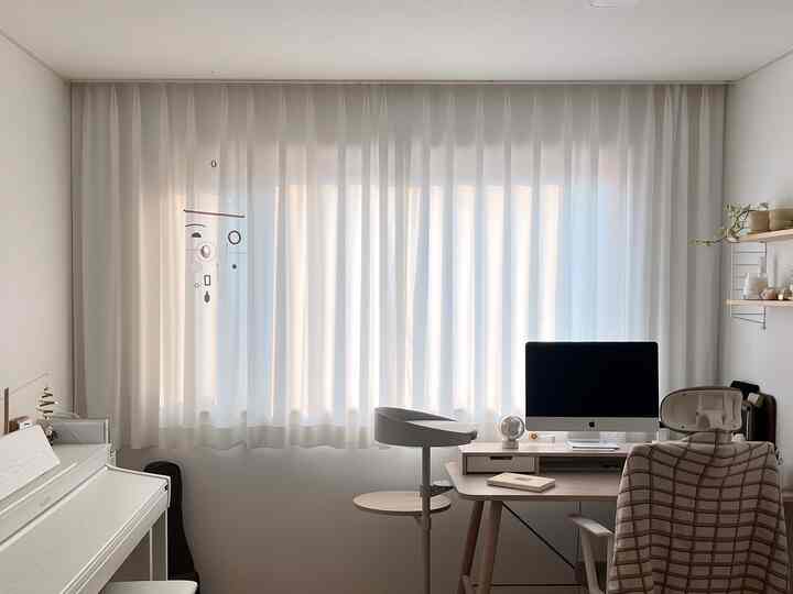 白とナチュラルカラーのホームオフィス、机とピアノが配置されたシンプルで落ち着いた雰囲気のインテリア