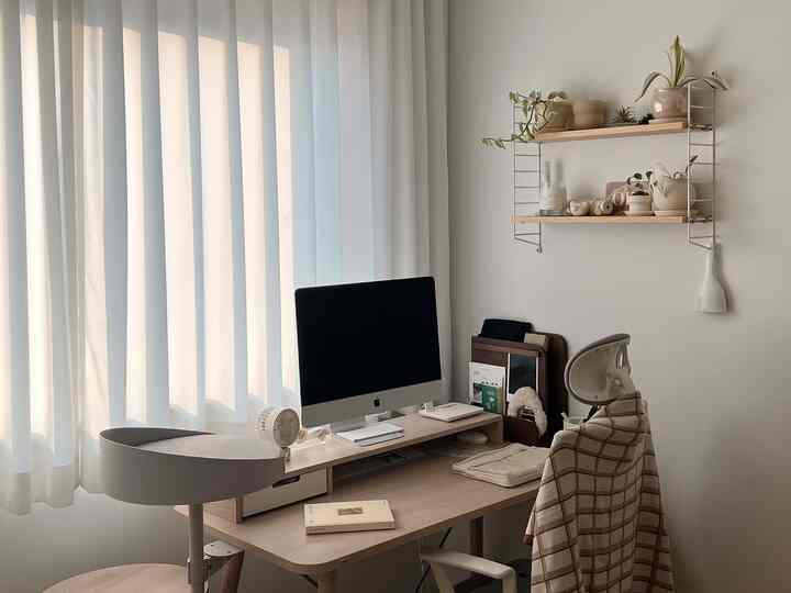 White and wood tone home office featuring a desk, office chair, and wall shelf with plants creating a calm atmosphere