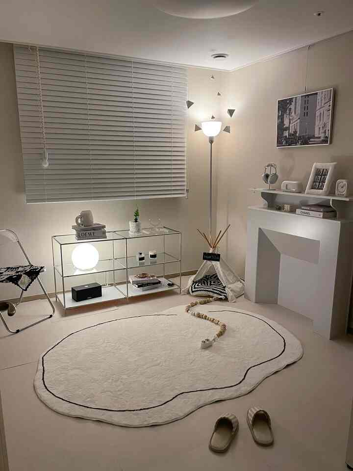 White and monotone living room featuring console table, floor lamp, and dog tent creating a simple and cozy atmosphere