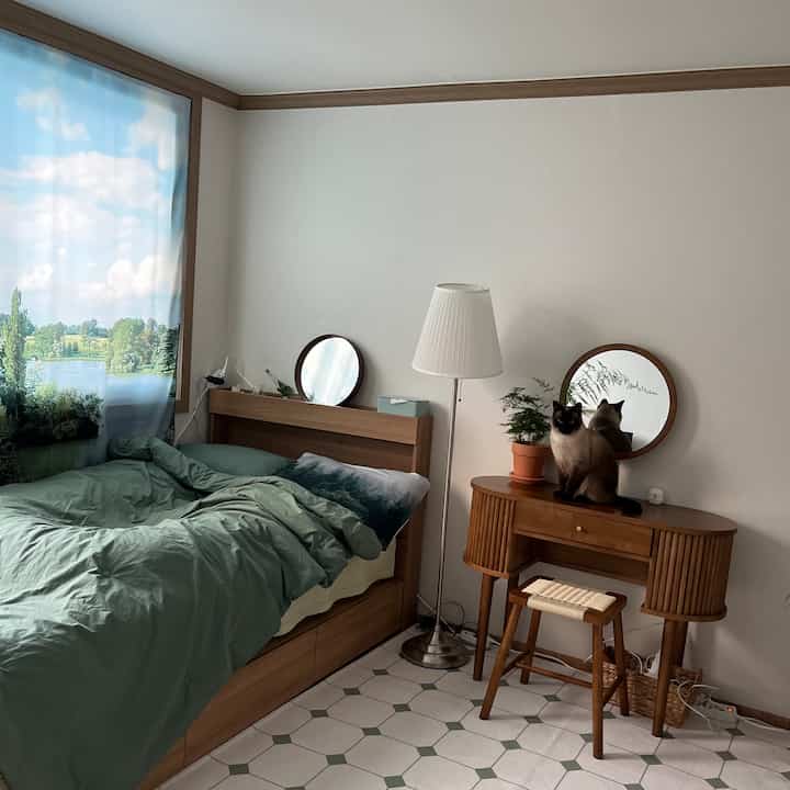 Wood tone and white bedroom featuring wooden bed frame, vanity, and a cat, creating a warm natural atmosphere
