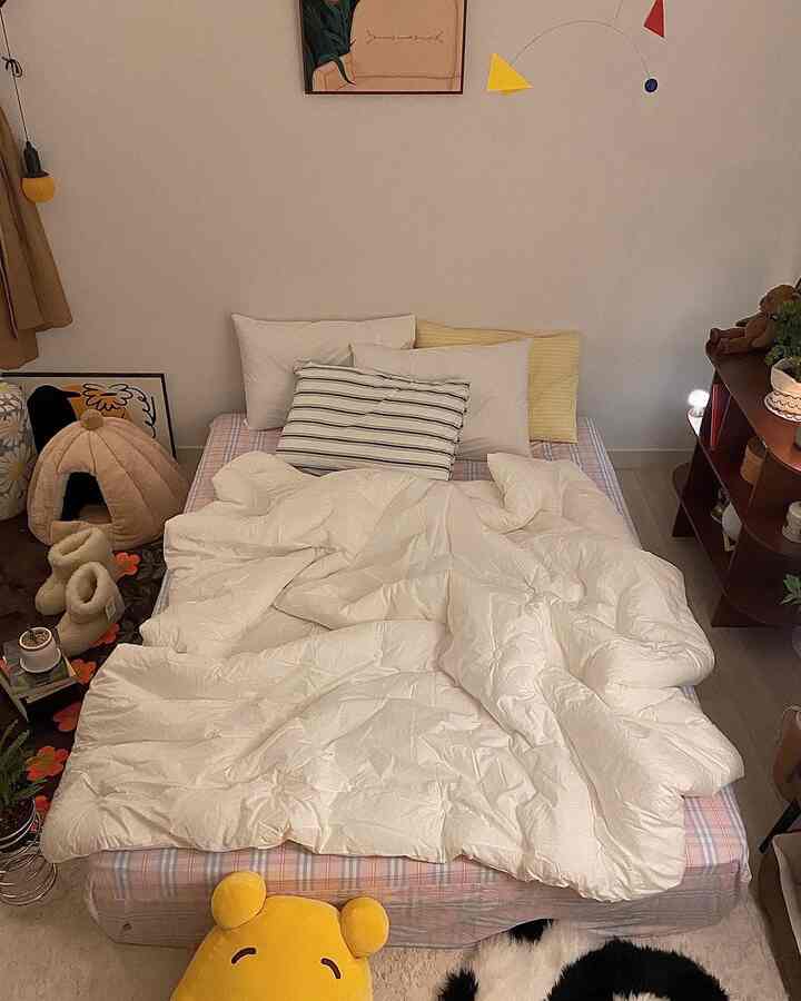 Cozy bedroom in warm ivory and beige tones featuring a central bed with fluffy duvet and pillows