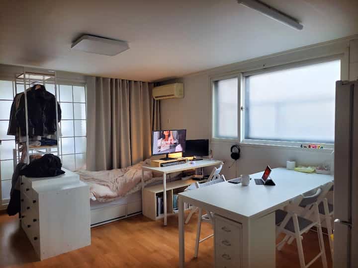 An 8-pyeong studio apartment in white and wood tones, featuring a bed, Desk, and dining table in a compact, neat single household interior.