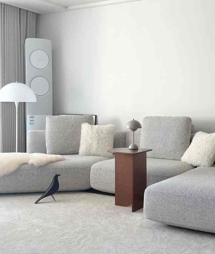 Gray and natural brown toned living room featuring a modular sofa and a half-moon side table in a modern setting