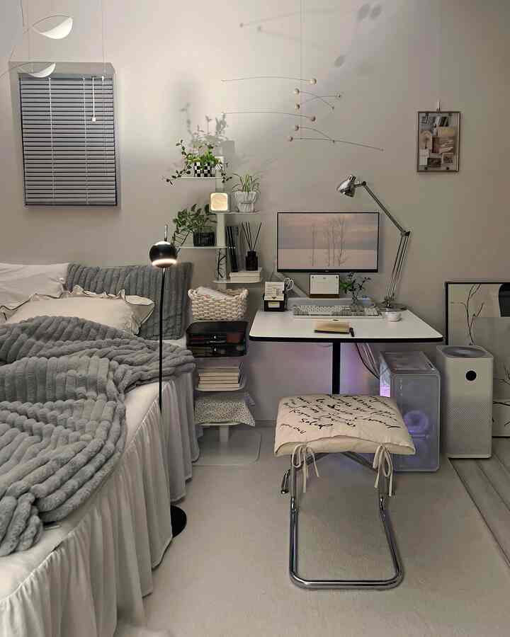 白とグレーのトーンの狭いワンルーム、ベッドとデスクが配置された自然でモダンなホームオフィスのある印象的な空間