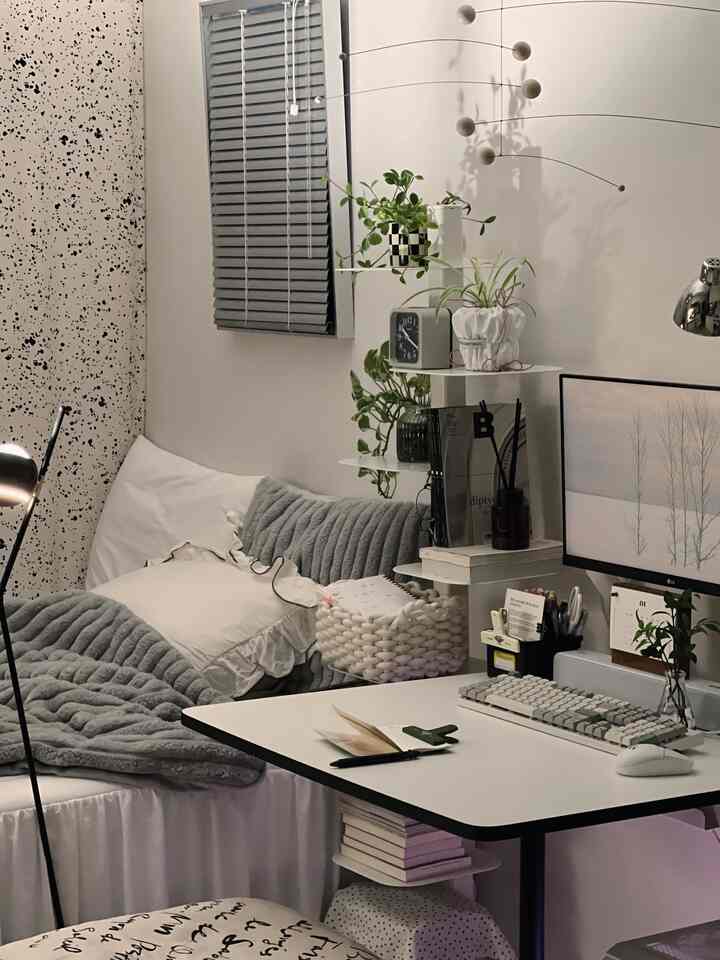 White and gray toned bedroom-style home office space featuring a desk with monitor and cushions for a cozy atmosphere