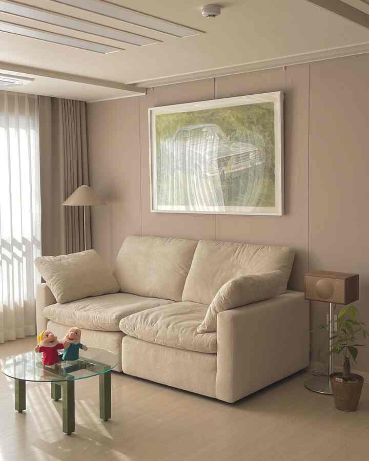 Natural beige-toned living room featuring a beige sofa, soft curtains, and framed artwork creating a warm atmosphere