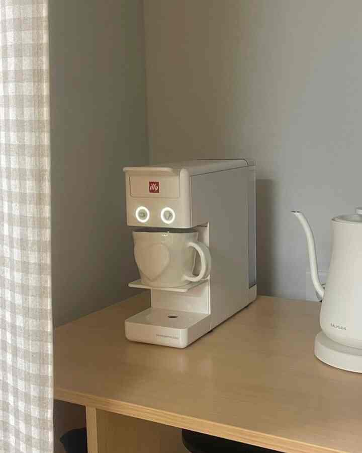 White and wood tone kitchen space featuring an illy coffee machine and Balmuda electric kettle, creating a simple and minimal home cafe atmosphere
