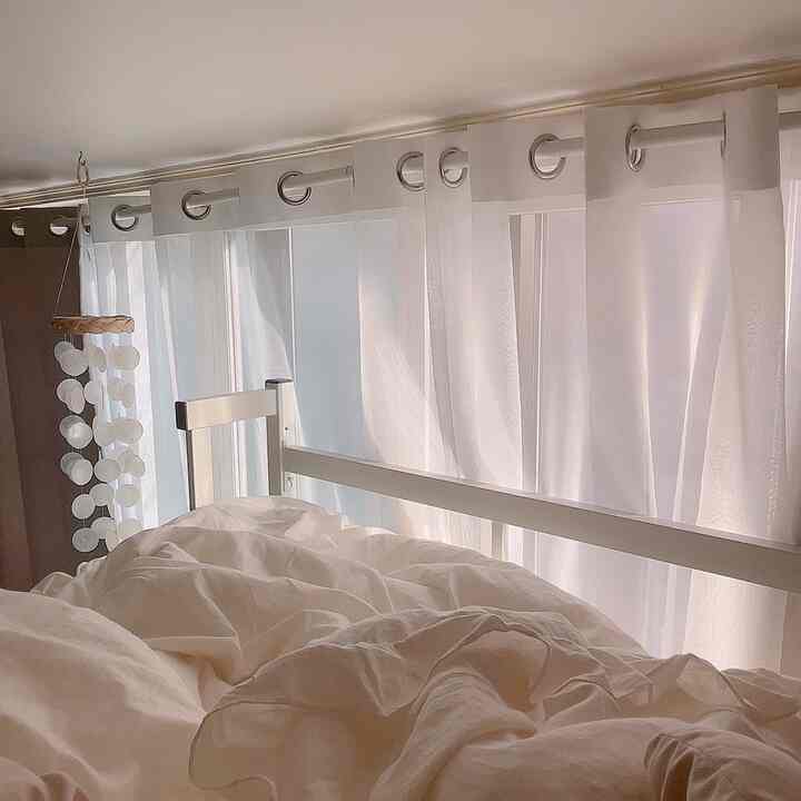 Bright white and natural-toned veranda bedroom featuring soft bedding and blackout curtains creating a cozy ambiance