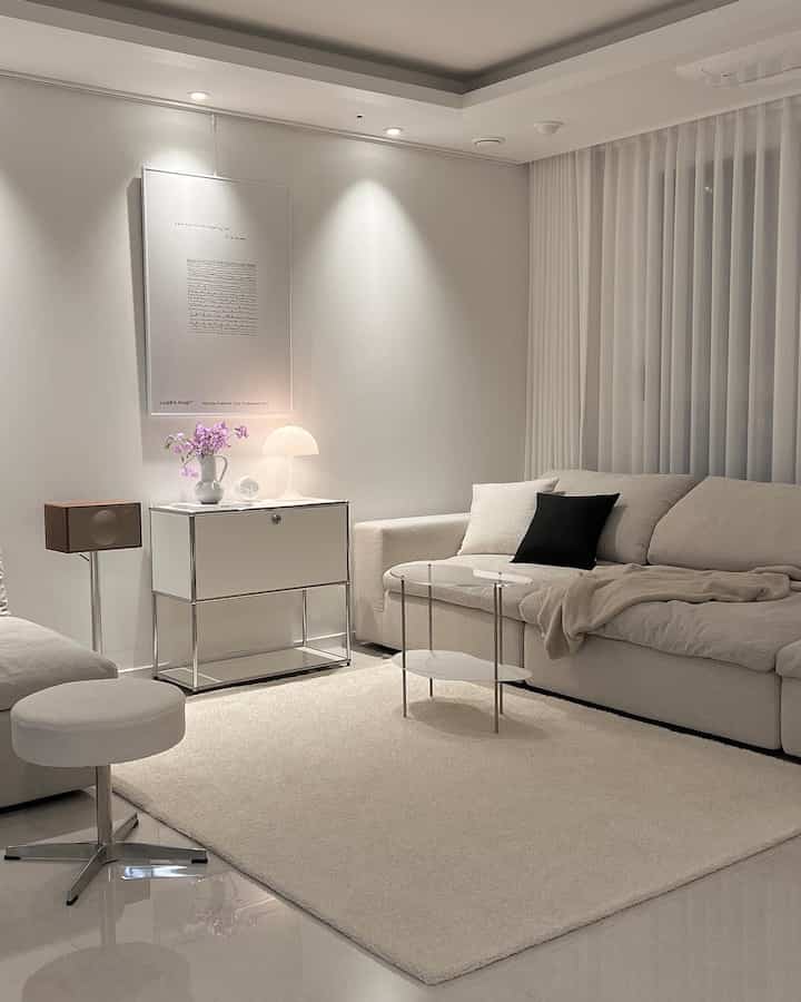 White and natural toned living room featuring a sectional sofa, rug, side table with warm and calm atmosphere