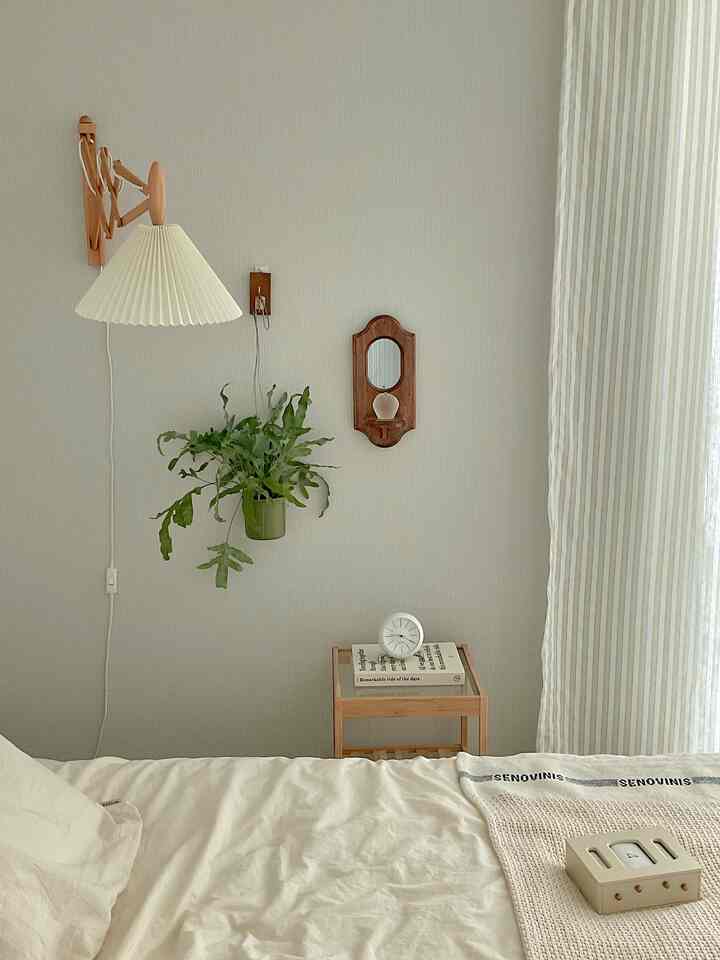 Natural and simple bedroom with white and wood tones, featuring a wall pleated lamp, clocks, and striped curtains