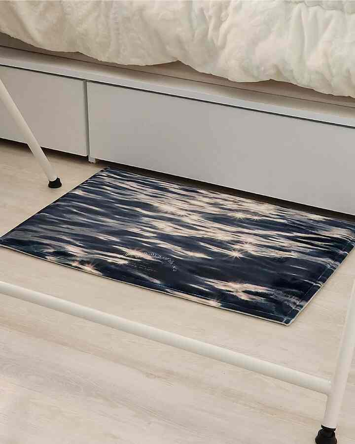 アイボリー調の寝室にネイビーのマイクロファイバー製バスマットが配置されたモダンな空間