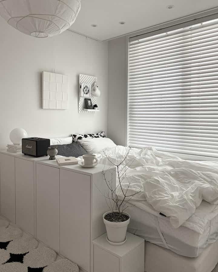 White-toned bedroom featuring neat storage units and large blinds in a natural modern style