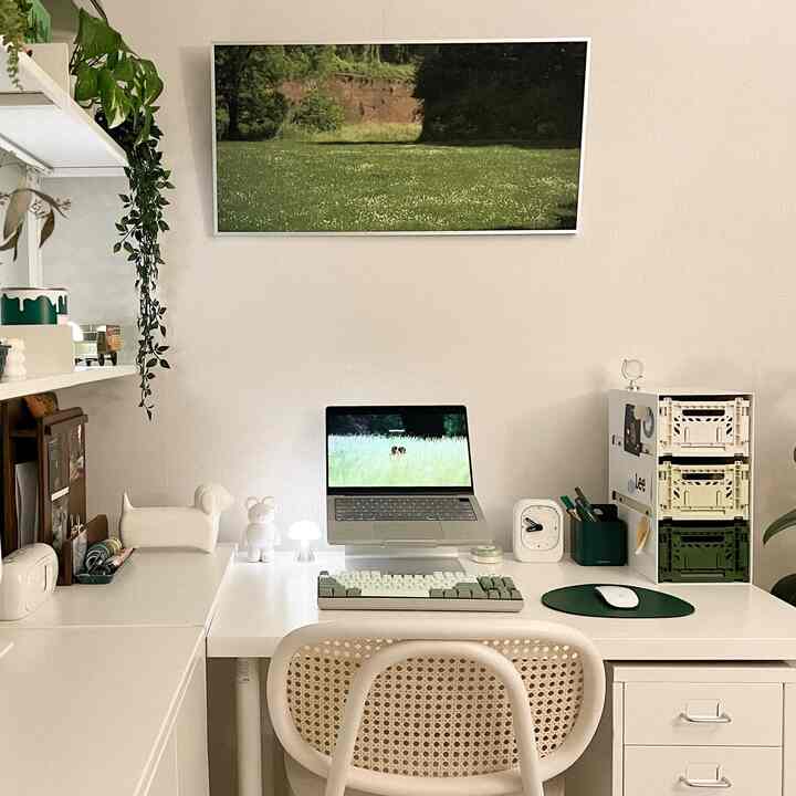 White and green toned home office space featuring an organized desk with laptop and modern minimalist style