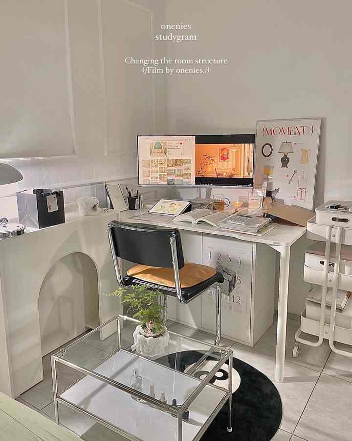 A white and black toned home office featuring a desk with monitors and a chair, displaying a simple and modern interior