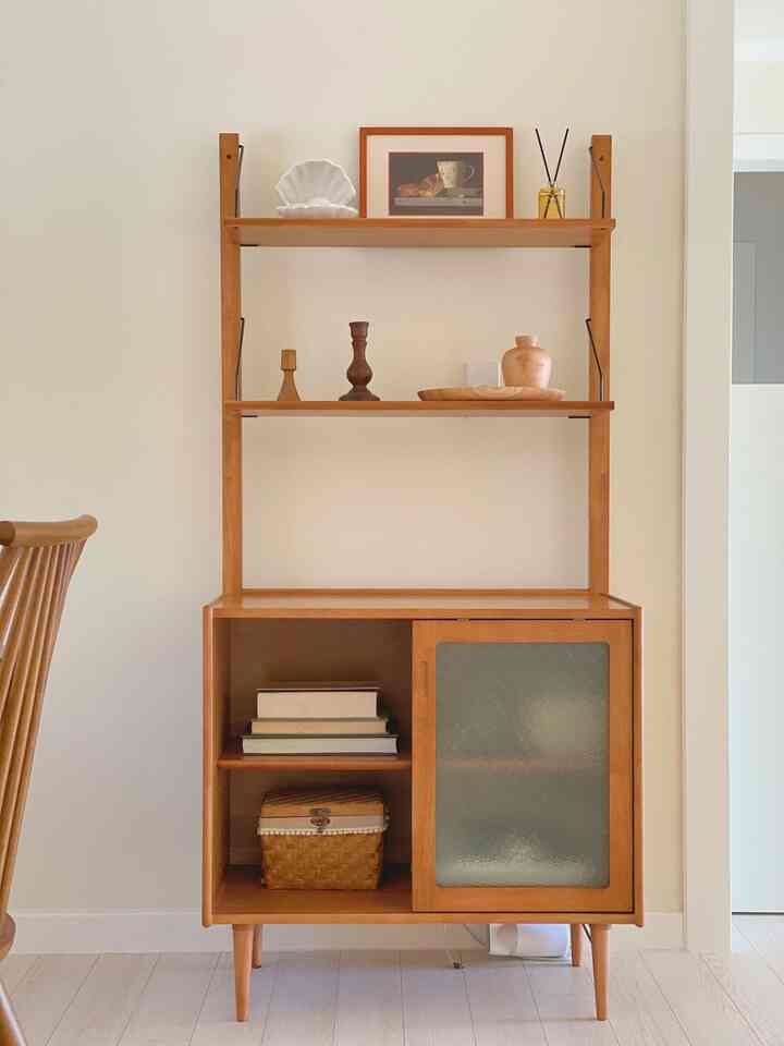 Natural wood tone wall shelf cabinet featuring decorative items in a cozy kitchen space